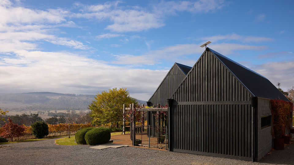 A Starlink dish on the roof of a black barn in a countryside setting.